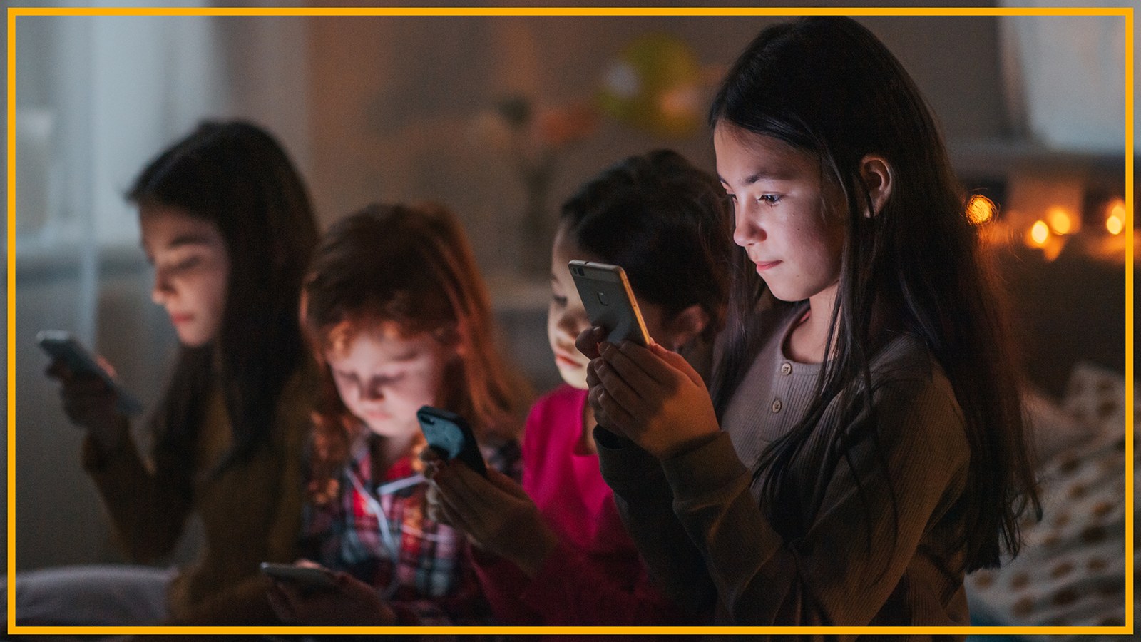 Four children look at their phones in a bedroom