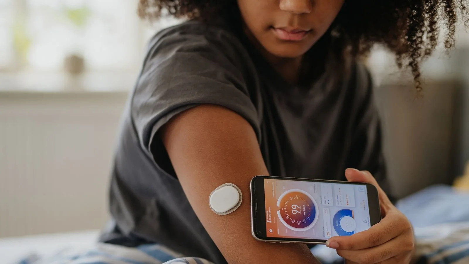 A woman scans a circular device on her arm with her phone