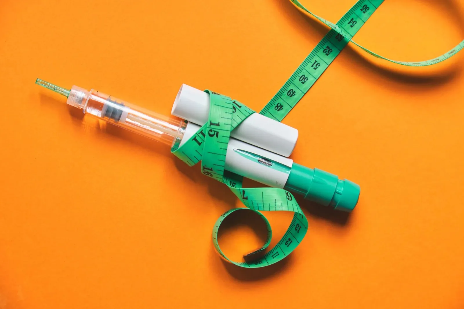 Glp-1 injection pen and tape measure symbolizing weight loss and obesity treatment | Image Credit: © rjankovsky - stock.adobe.com