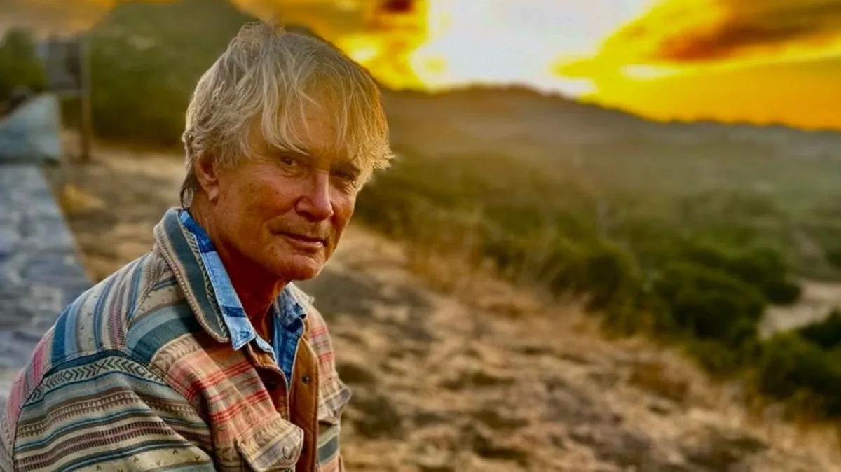 Richard Norton sits on a bench with the sun setting behind him